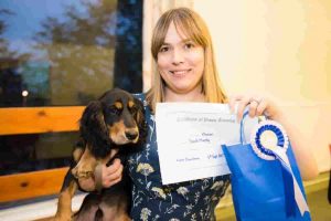 Cocker Spaniel puppy owner holding puppy with Puppy School certificate and rosette on graduation